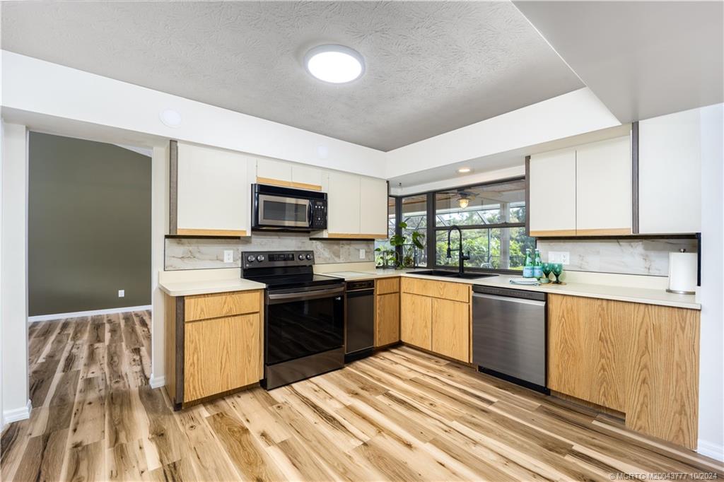 2556 Captiva Cove Stuart, FL 34994 - Photo 43 of 68 a kitchen with stainless steel appliances granite countertop a stove top oven a sink dishwasher and a refrigerator with wooden floor