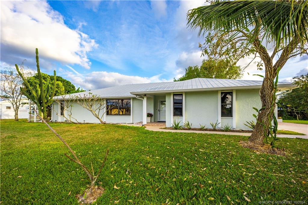 2556 Captiva Cove Stuart, FL 34994 - Photo 6 of 68 a front view of a house with a garden and trees