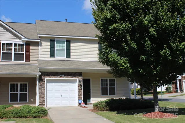 a front view of a house with a garden and trees