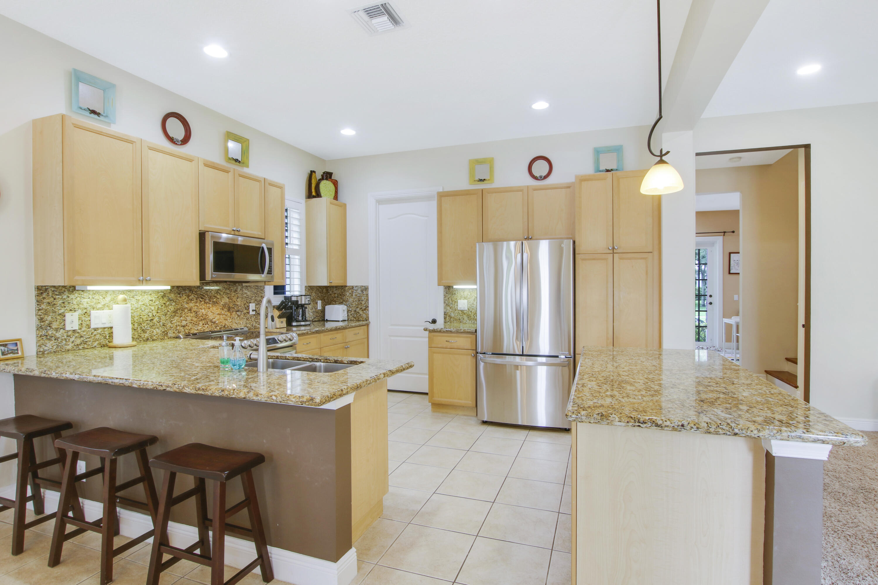 108 Spikerush Road Jupiter, FL 33458 - Photo 3 of 9 a kitchen with stainless steel appliances granite countertop a sink and a refrigerator
