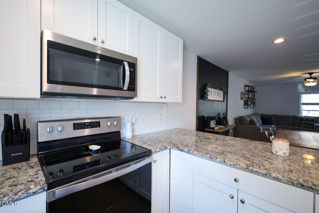 230 South Raleigh Street Angier, NC 27501 - Photo 8 of 38 a kitchen with granite countertop stainless steel appliances a stove microwave and sink