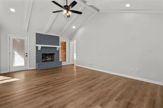 an empty room with wooden floor a fireplace and a ceiling fan