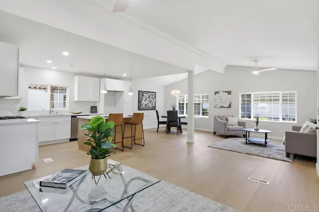 a living room with furniture kitchen view and a large window