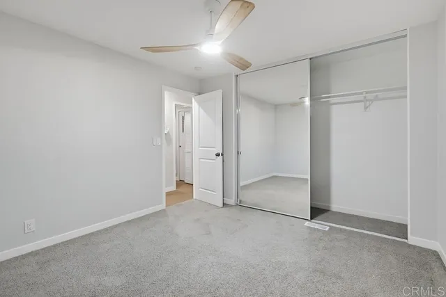 an empty room with closet and a chandelier fan