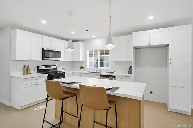 a kitchen with a refrigerator a stove a sink and chairs