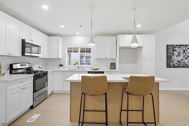 a kitchen with stainless steel appliances granite countertop a stove a sink a stove a refrigerator a microwave oven with white cabinets and cabinets