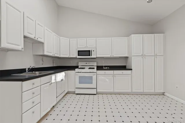a kitchen with granite countertop white cabinets and appliances