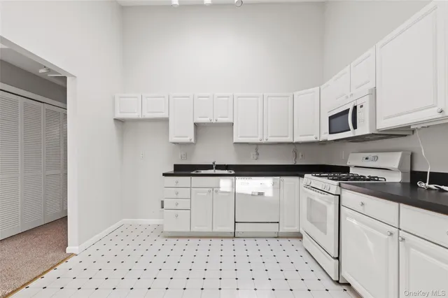 a kitchen with granite countertop a sink a stove and cabinets