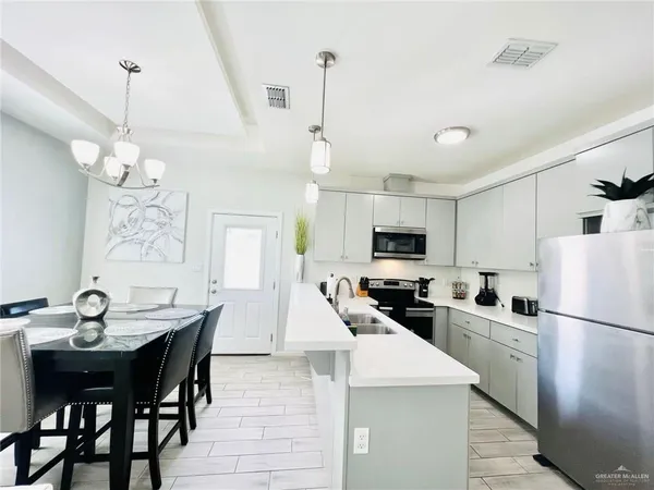 a kitchen with stainless steel appliances granite countertop a stove a refrigerator a kitchen island a sink a dining table and chairs with wooden floor