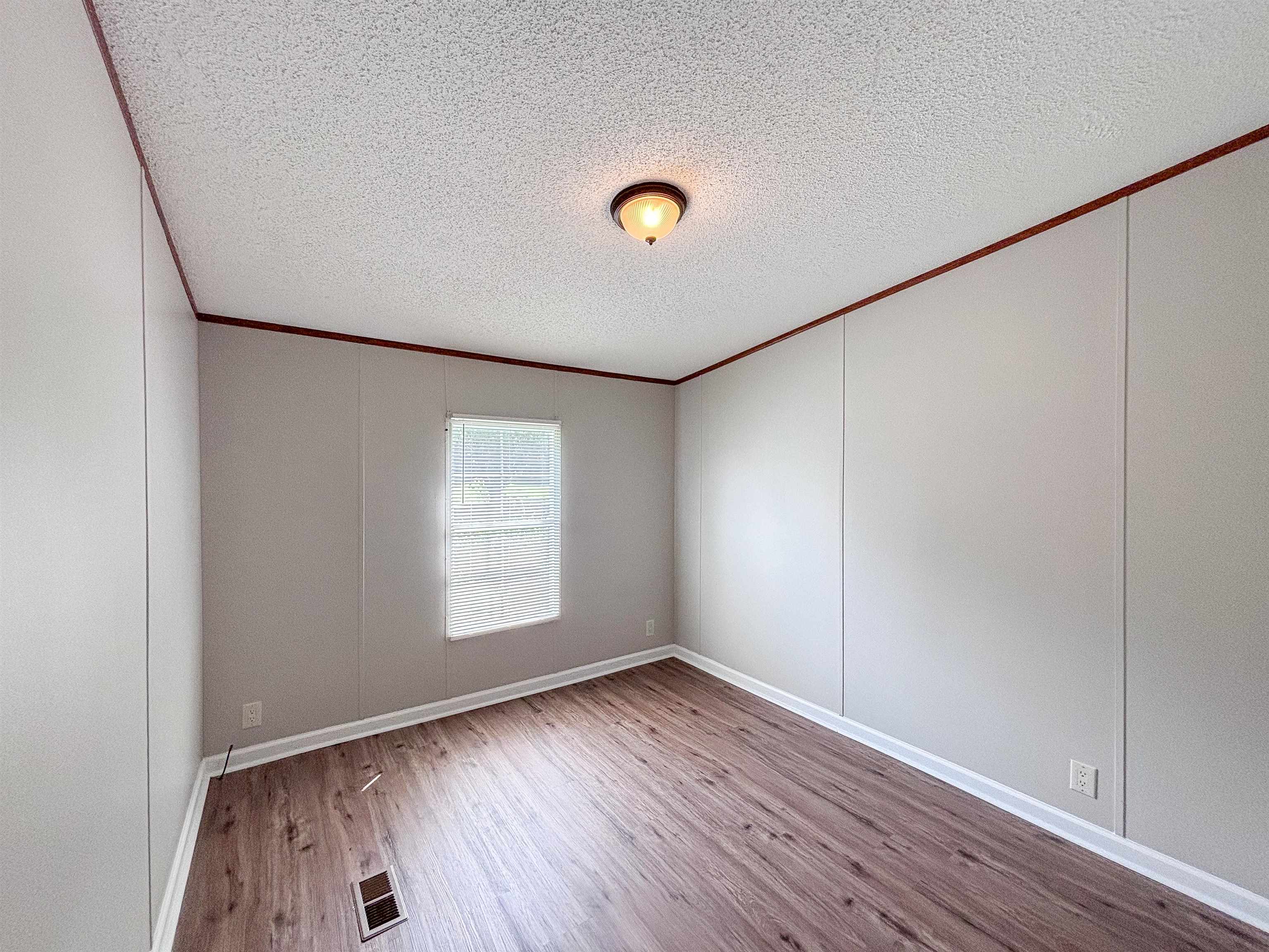 2847 Holly Grove Road Covington, TN 38019 - Photo 29 of 36 Interior room featuring wood-finish flooring, light gray paneled walls, white trim, and a window with natural light