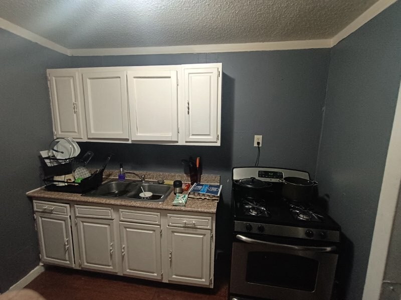 11914 Anchick Street Houston, TX 77076 - Photo 3 of 13 a kitchen with white cabinets and black appliances