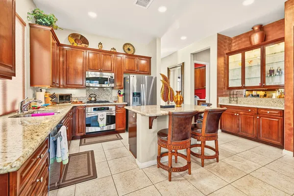 a kitchen with stainless steel appliances kitchen island granite countertop a table chairs and a refrigerator