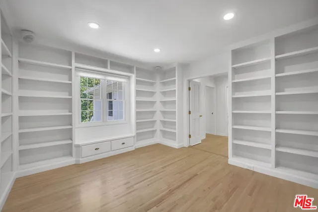 a view of an empty room with a window and wooden shelves