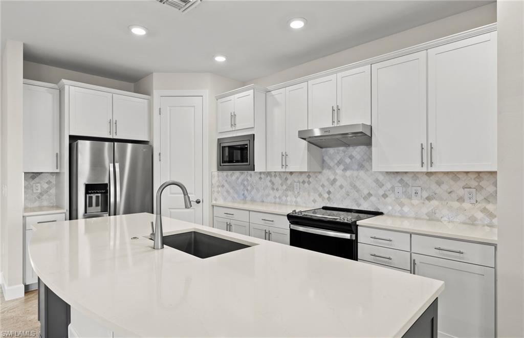 17039 Oakstead Drive Alva, FL 33920 - Photo 11 of 49 a kitchen with stainless steel appliances a sink a stove a refrigerator with white cabinets