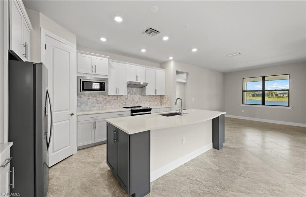 17039 Oakstead Drive Alva, FL 33920 - Photo 13 of 49 a kitchen with kitchen island a sink a stove a refrigerator and a refrigerator