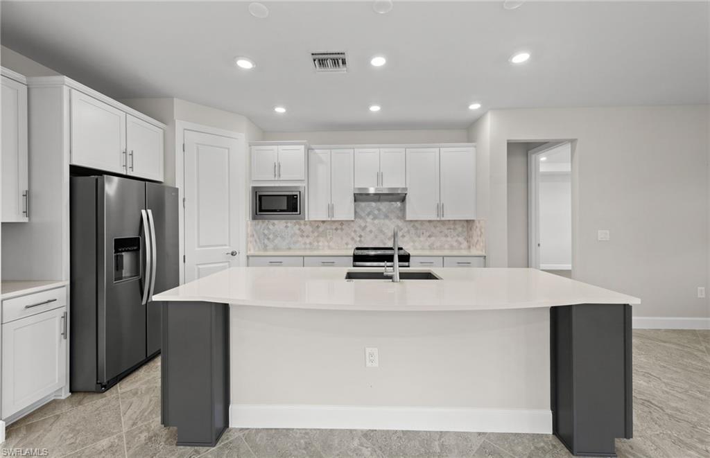 17039 Oakstead Drive Alva, FL 33920 - Photo 14 of 49 a kitchen with stainless steel appliances granite countertop a refrigerator a sink a stove a microwave and white cabinets