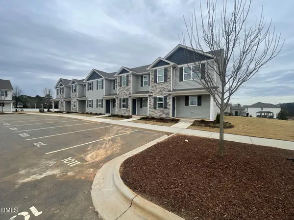 a view of a white house with a yard next to a road