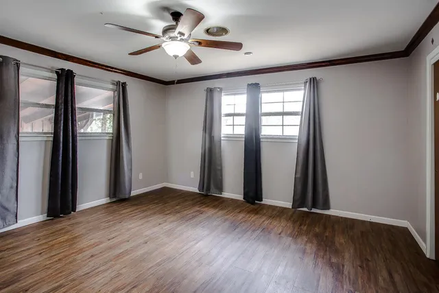 a view of an empty room with window and wooden floor