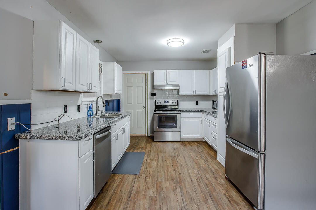 4402 28th Street Lubbock, TX 79410 - Photo 4 of 18 a kitchen with stainless steel appliances granite countertop a refrigerator a sink dishwasher a stove and white countertops with wooden floor