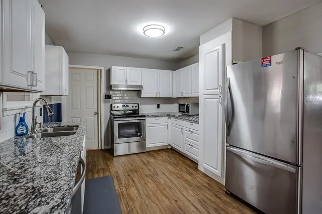 a kitchen with granite countertop a refrigerator stove and sink