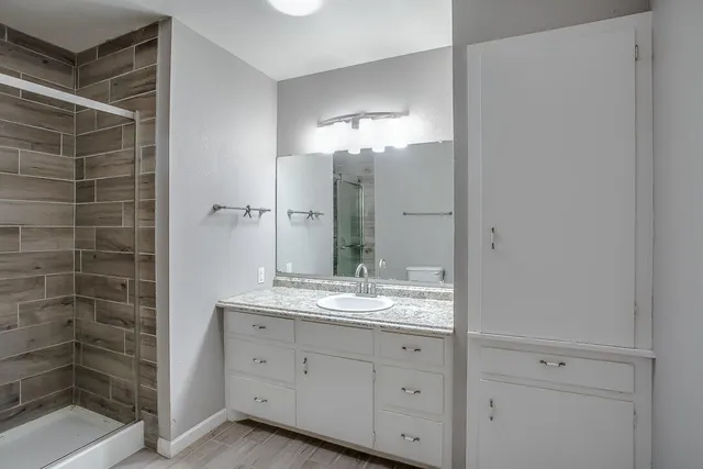 a bathroom with a granite countertop sink a mirror and a shower