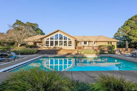 a view of a house with pool and a yard