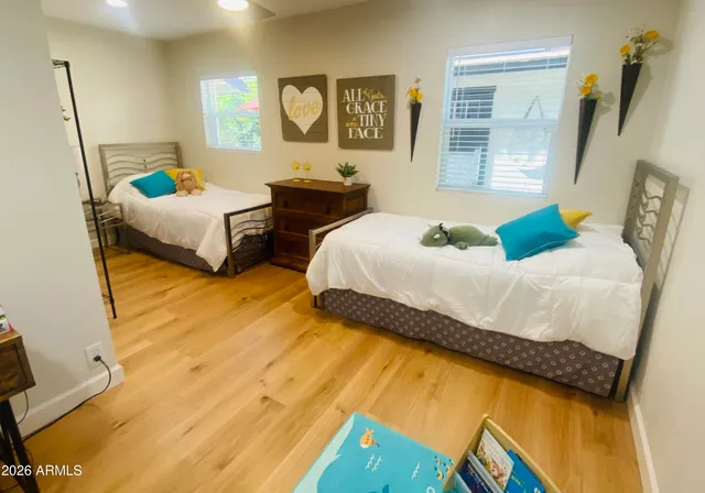 a bedroom with two beds and a dresser next to a window