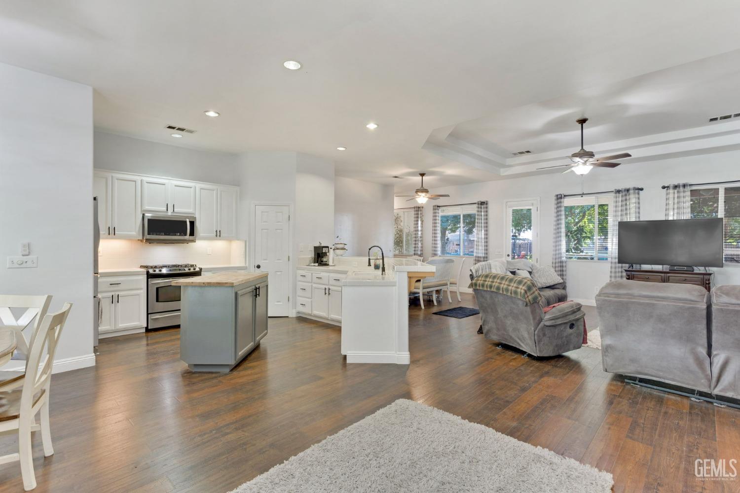 Undisclosed Address Bakersfield, CA 93314 - Photo 5 of 36 a large open kitchen with a refrigerator a stove top oven a sink dishwasher and white cabinets with wooden floor