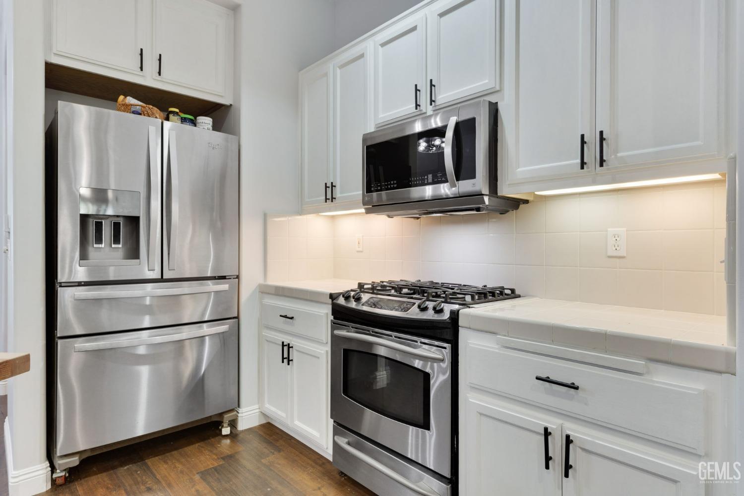 Undisclosed Address Bakersfield, CA 93314 - Photo 7 of 36 a kitchen with stainless steel appliances white cabinets and a wooden floor