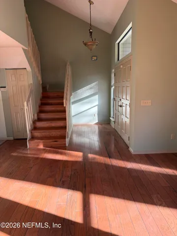 a view of an empty room with wooden floor and doors