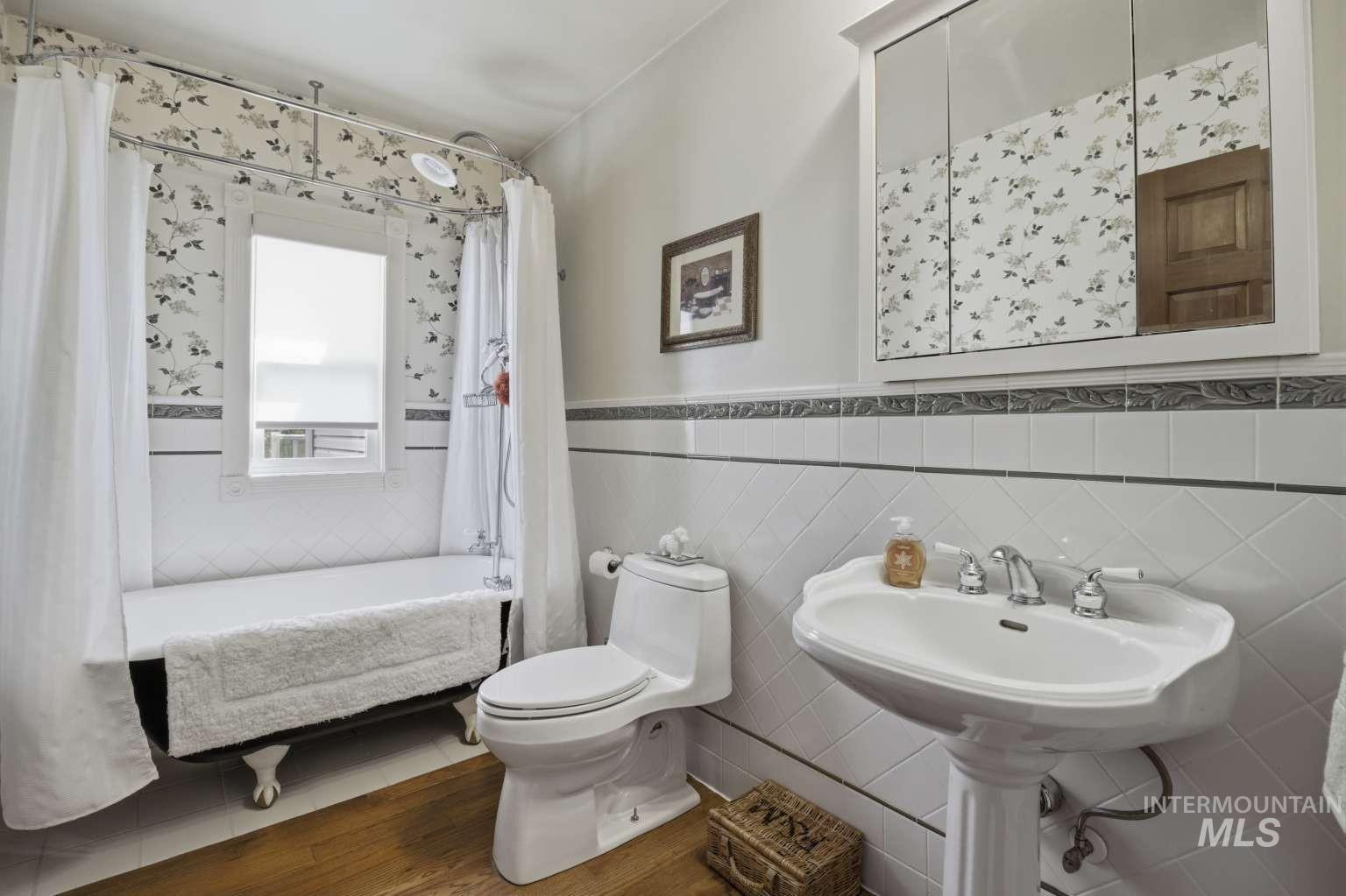901 Main Street Kendrick, ID 83537 - Photo 25 of 50 Bathroom featuring a clawfoot tub, pedestal sink, and wood-finish flooring