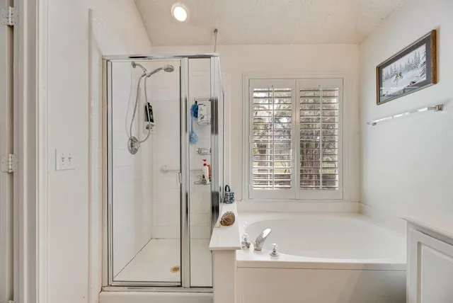 a spacious bathroom with a double vanity sink a mirror a bathtub and shower