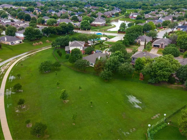 a view of a lake with a yard and large trees