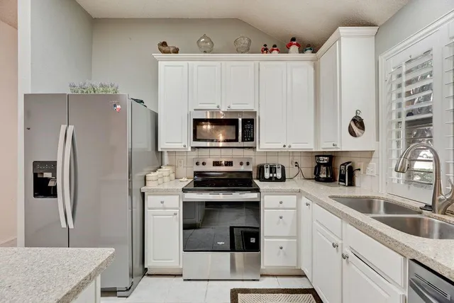 a kitchen with white cabinets and stainless steel appliances