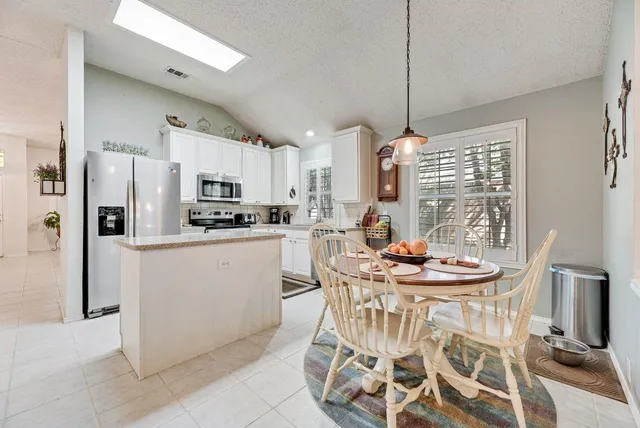 a kitchen with stainless steel appliances kitchen island granite countertop a refrigerator a stove a microwave oven a dining table and chairs with wooden floor