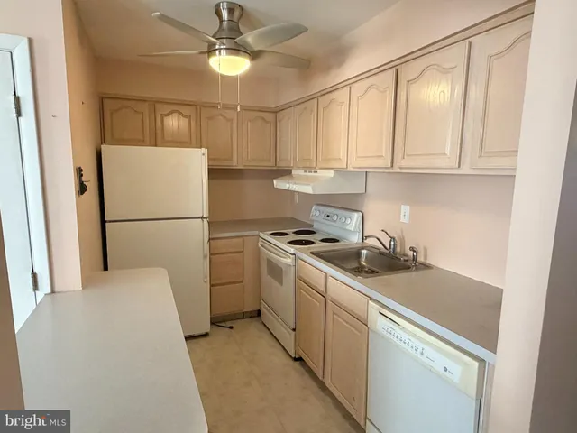 a kitchen with a sink a refrigerator a stove and white cabinets