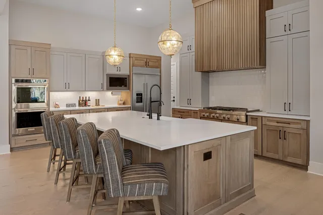 a large kitchen with kitchen island a large window a sink and stainless steel appliances