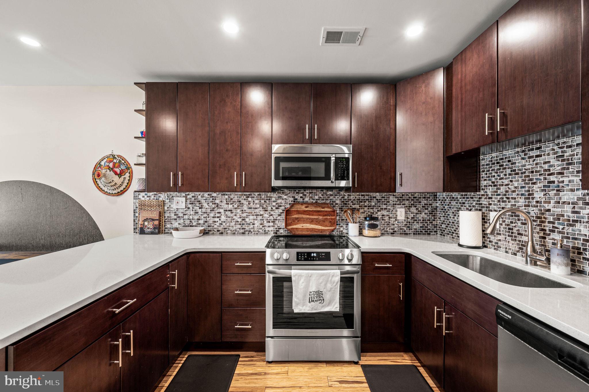 1825 Carpenter Street, Unit A Philadelphia, PA 19146 - Photo 6 of 25 a kitchen with stainless steel appliances kitchen island granite countertop a sink stove and microwave