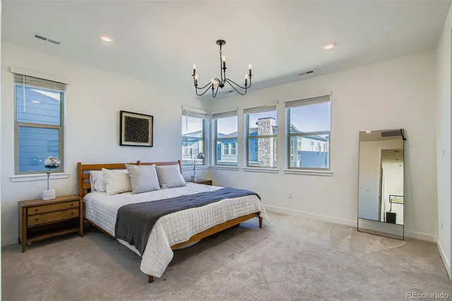 a spacious bedroom with a bed chandelier and windows