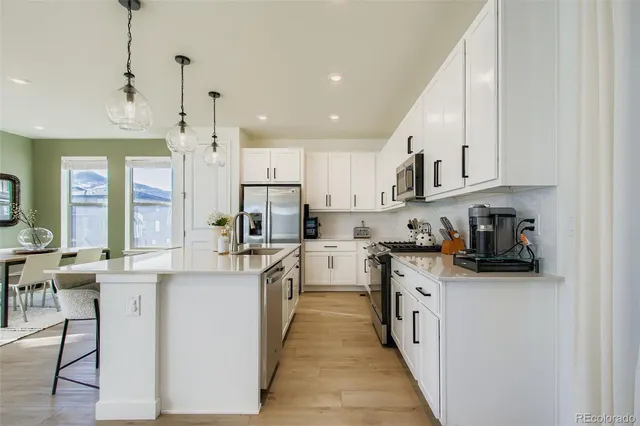 a kitchen with stainless steel appliances granite countertop a stove top oven a refrigerator a sink and dishwasher with white cabinets