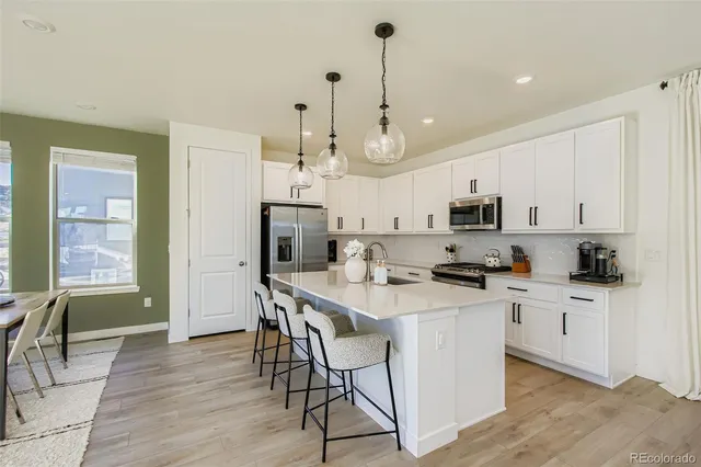 a kitchen with stainless steel appliances kitchen island a table chairs refrigerator and microwave