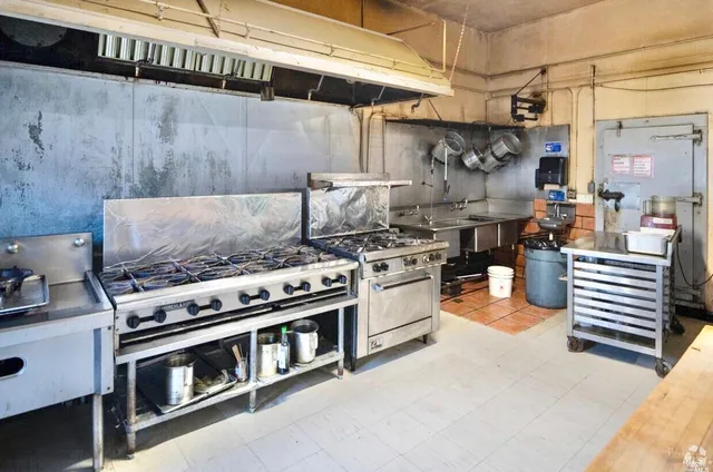 a view of a refrigerator in kitchen and an empty room