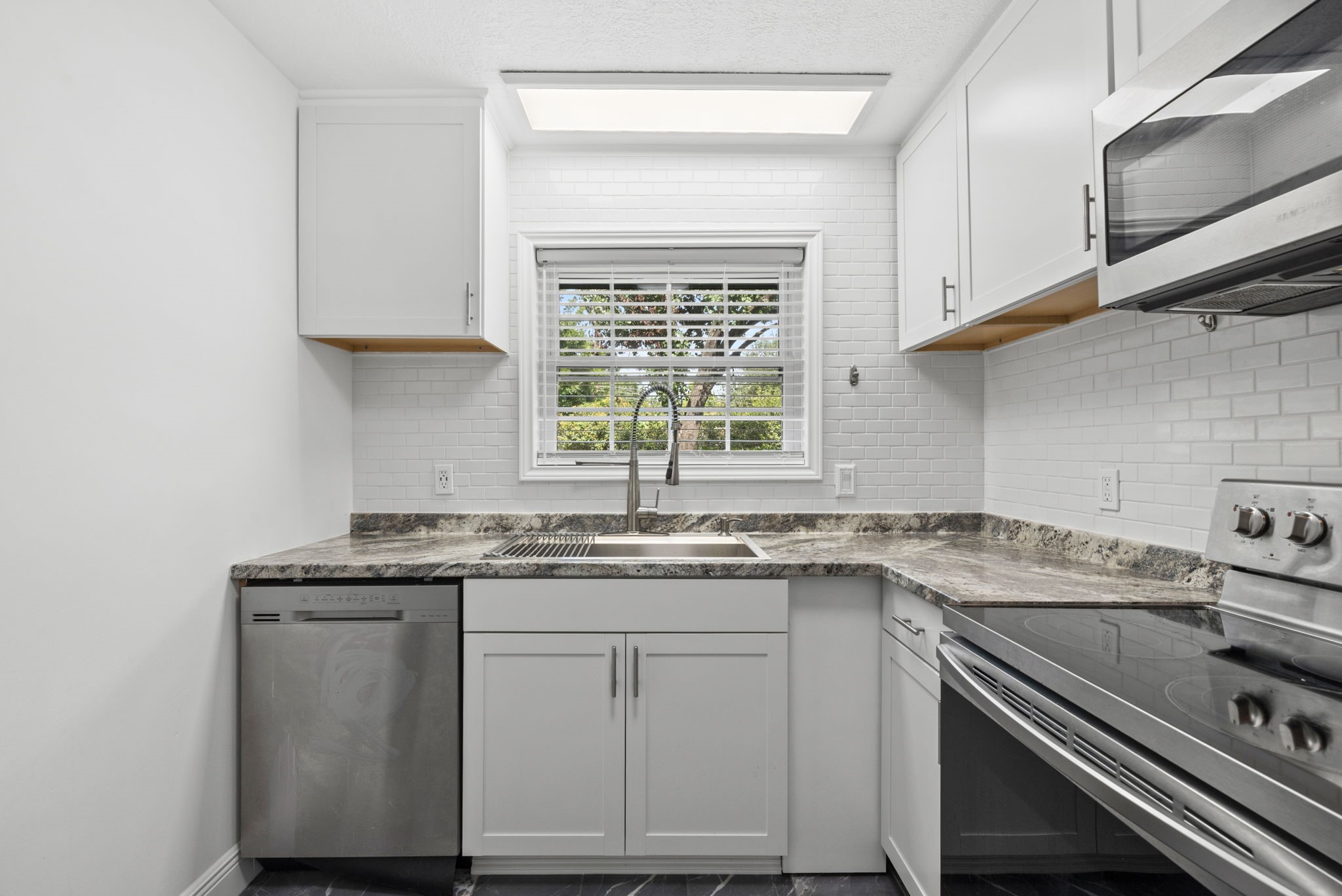 7900 Westheimer Road, Unit 121 Houston, TX 77063 - Photo 13 of 23 Bright and modern kitchen featuring sleek stainless steel appliances, elegant marble countertops, and a stylish subway tile backsplash.