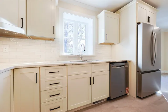 a kitchen with white cabinets and refrigerator