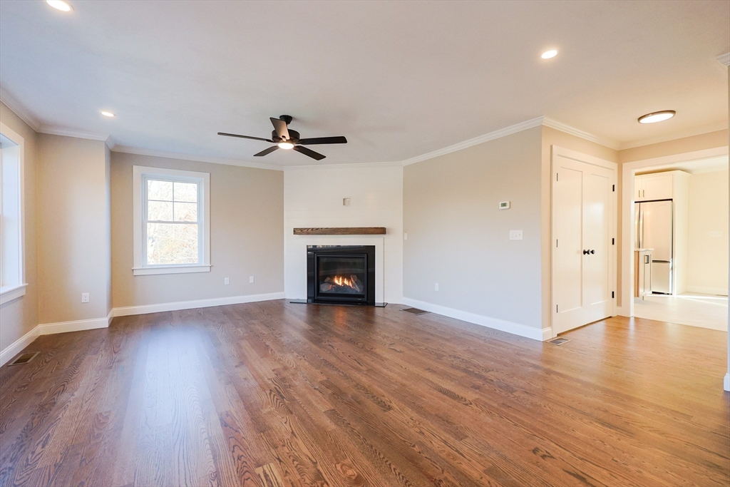 58 Baltic Street, Unit 58 Attleboro, MA 02703 - Photo 13 of 34 an empty room with wooden floor a ceiling fan a fireplace and windows