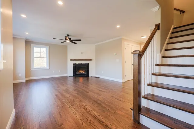 a view of an empty room with wooden floor fireplace and a window