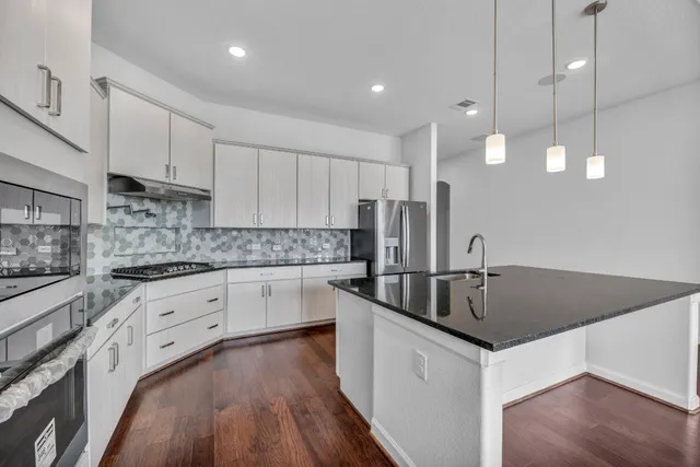 a kitchen with stainless steel appliances granite countertop a sink a stove and a granite counter tops