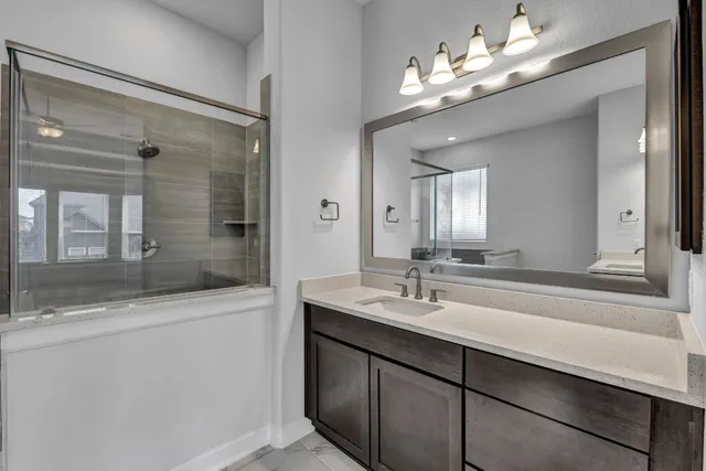a bathroom with a sink double vanity granite tub shower and a mirror