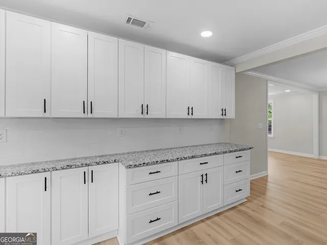 a large white kitchen with granite countertop a stove top oven a sink and white cabinets
