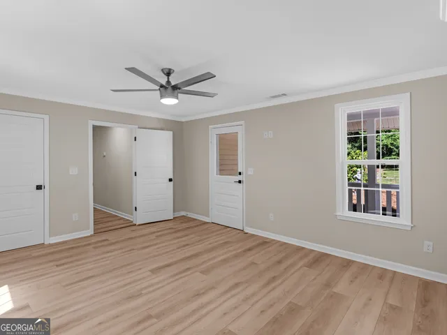 a view of empty room with wooden floor and fan